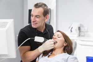 Dentist scanning patient's teeth with CEREC (Chairside Economical Restoration of Esthetic Ceramics) scanner