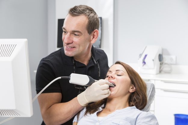 Dentist scanning patient’s teeth with a CEREC scanner