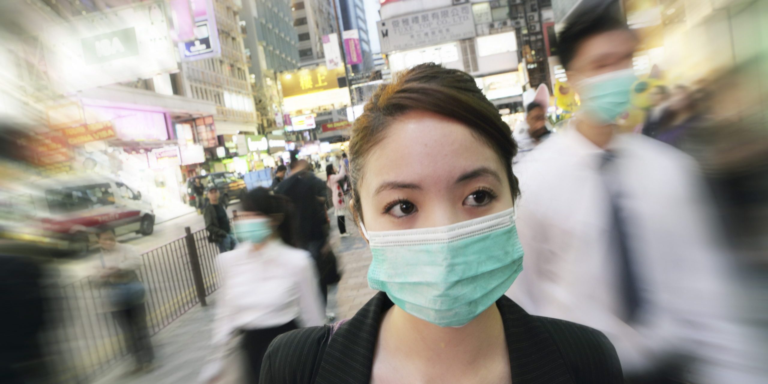 Young business woman wears mask as she walks through the city