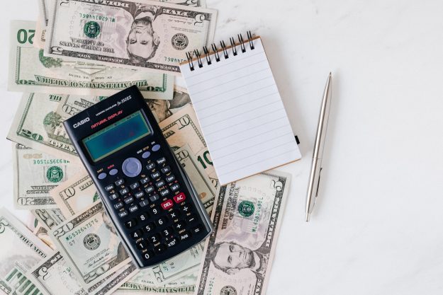Canva – Calculator and notepad placed over stack of USA dollars